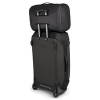 Osprey Transporter Global Carry On Bag hooked onto wheeled luggage